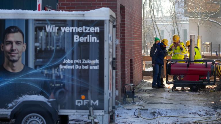 Mitarbeiter des Umspannwerkes an der Argentinischen Allee stehen hinter einem Zaun nebeneinander.