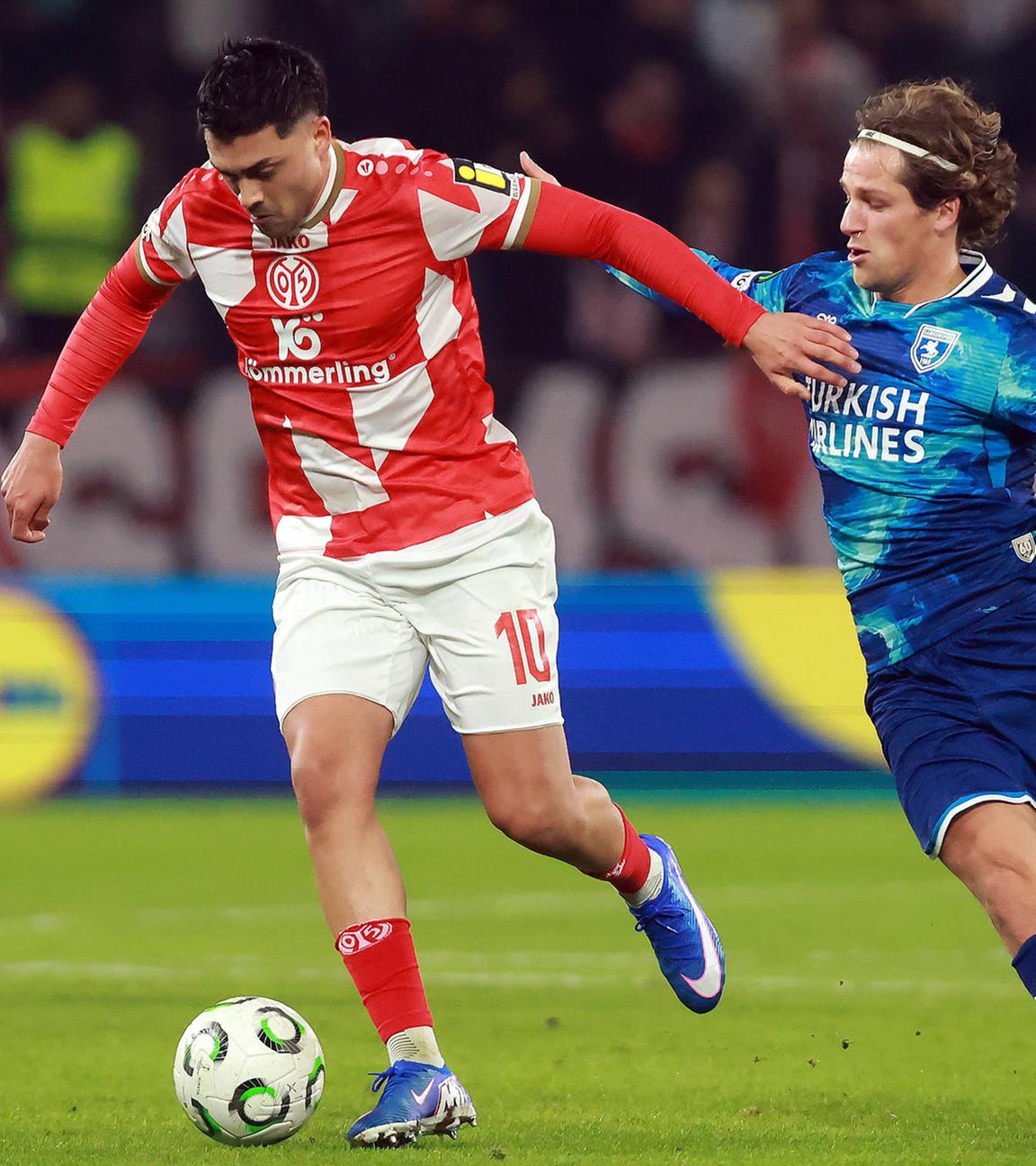 Nadiem Amiri (1. FSV Mainz 05, Nr. 10, rot) und Carlo Holse (Samsunspor, Nr. 21, blau) kämpfen um den Ball im Spiel der Conference League