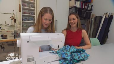 Designerin Stefanie Behling sitzt mit einer jungen Frau an der Nähmaschine.