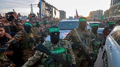 Kämpfer der Hamas kontrollieren die Menschenmenge, während Fahrzeuge des Roten Kreuzes manövrieren, um israelische Geiseln einzusammeln, die im Rahmen eines Waffenstillstandsabkommens zwischen Israel und der Hamas in Gaza-Stadt freigelassen werden sollen