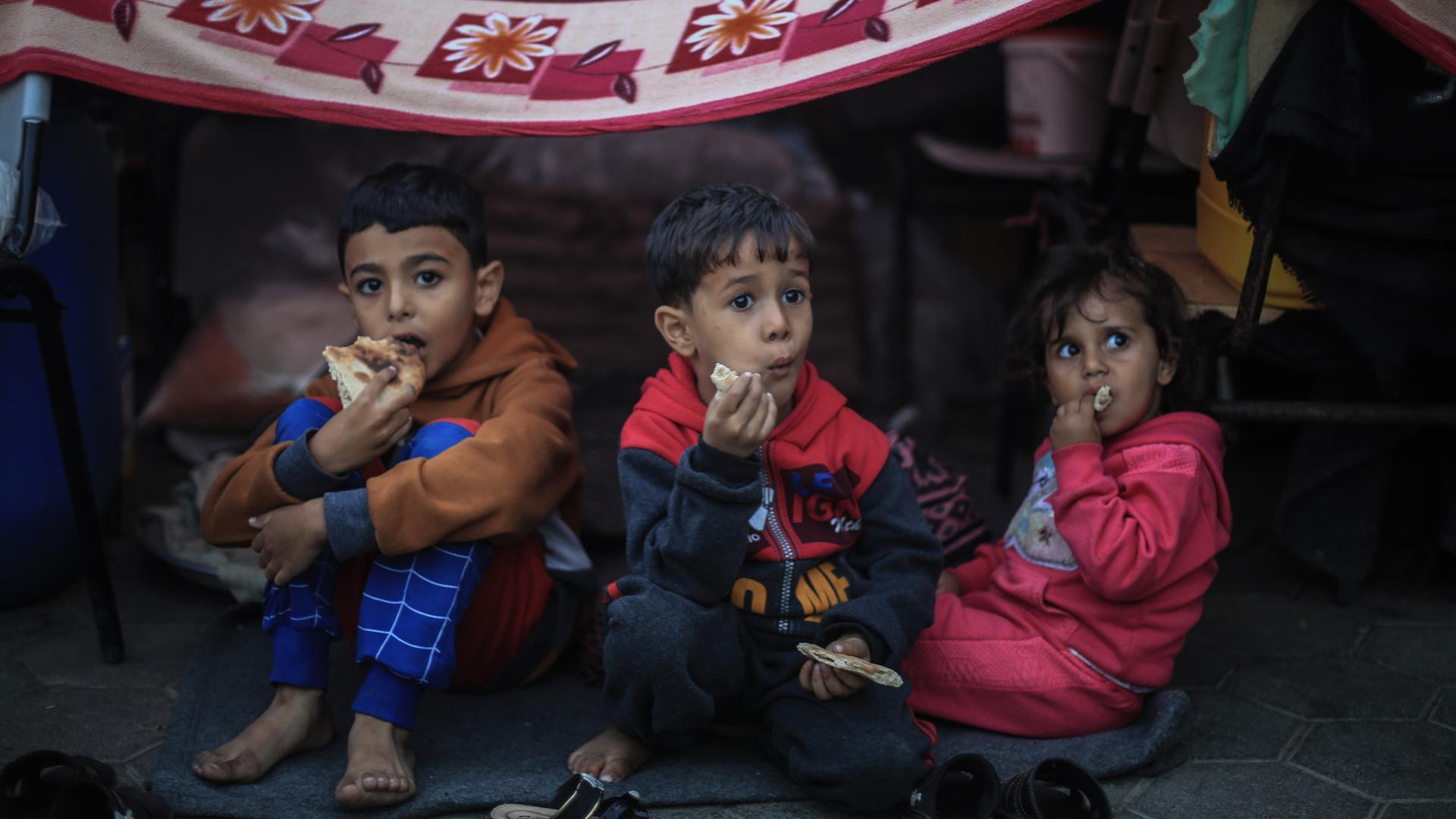 Drei Kinder sitzen in einer Schule in Chan Yunis im südlichen Gazastreifen.