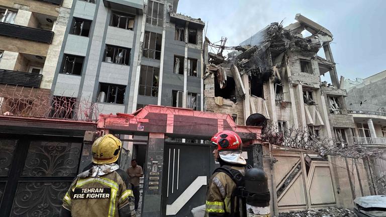 Einsatzkräfte versammeln sich vor einem Gebäude, das am 13.06.2025 in Teheran von einem israelischen Angriff getroffen wurde.