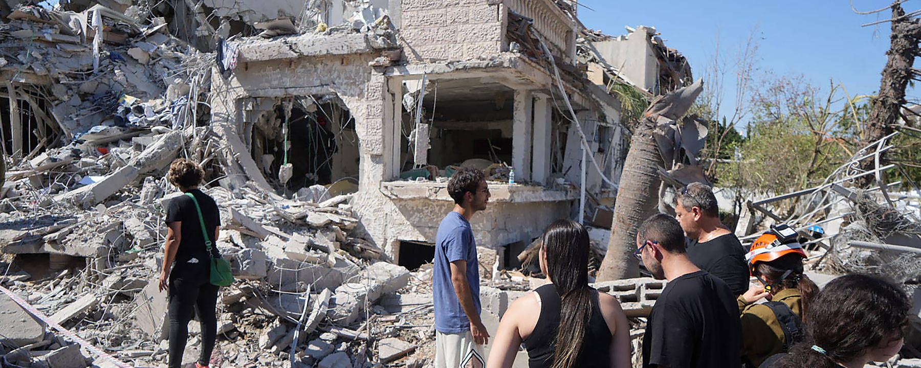 Menschen gehen am 14.06025 durch die Trümmer eines zerstörten Gebäudes in Rischon LeZion (Israel)