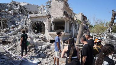 Menschen gehen am 14.06025 durch die Trümmer eines zerstörten Gebäudes in Rischon LeZion (Israel)
