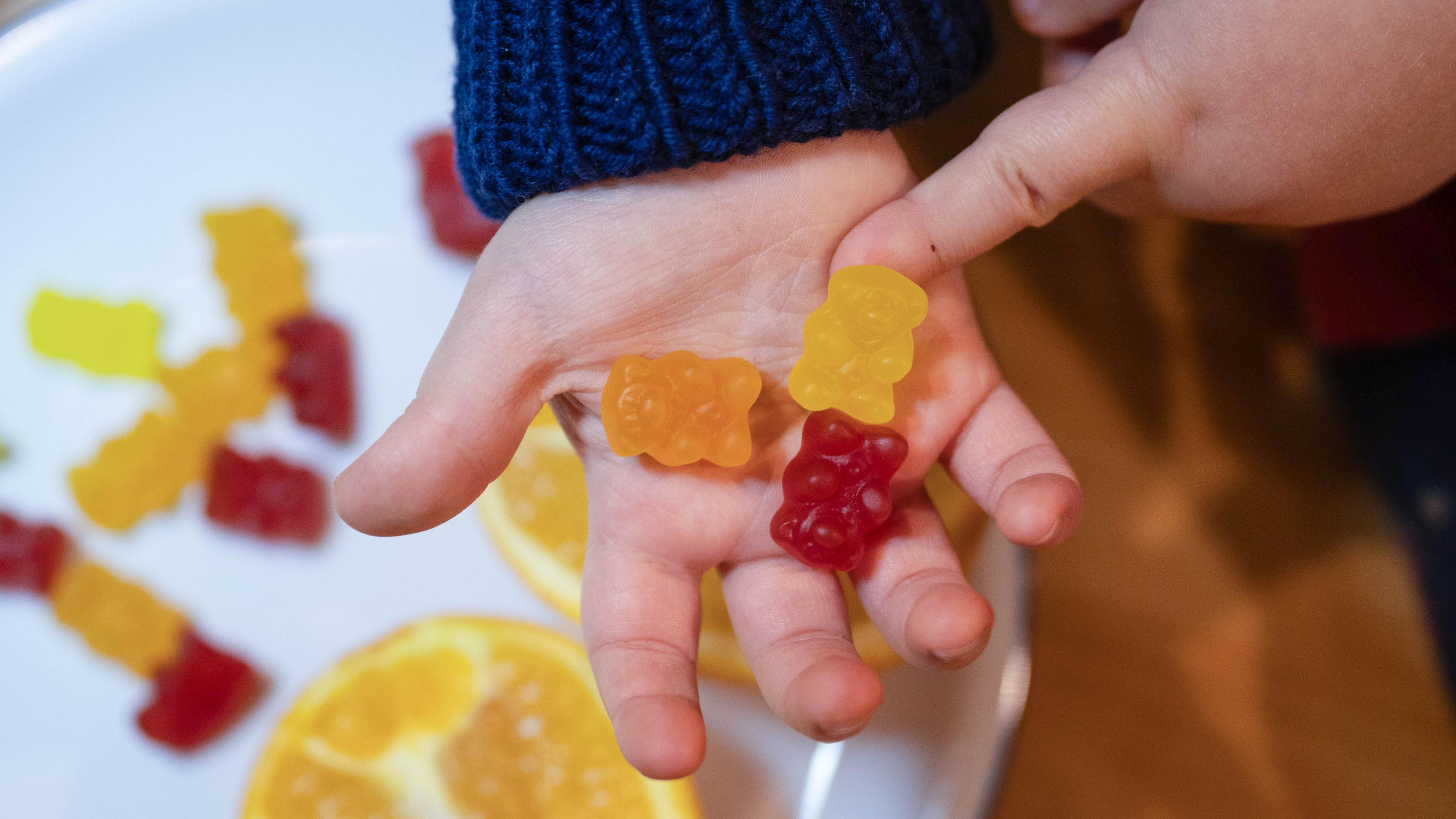 Kind hält Kinder-Vitaminbärchen in der Hand