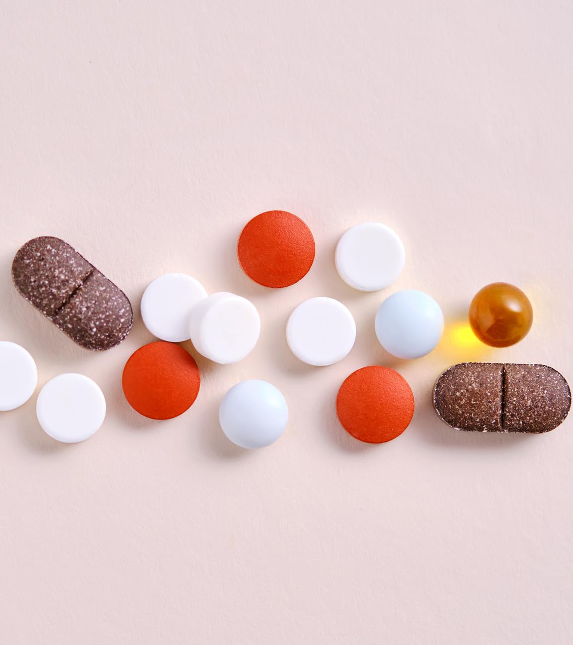 Pillen, Vitamine und Nahrungsergänzungsmittel auf einem beigen Hintergrund.