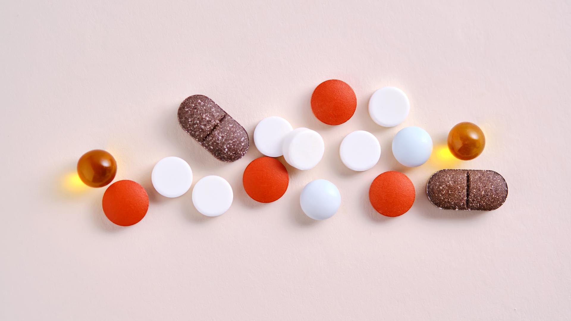 Pillen, Vitamine und Nahrungsergänzungsmittel auf einem beigen Hintergrund.