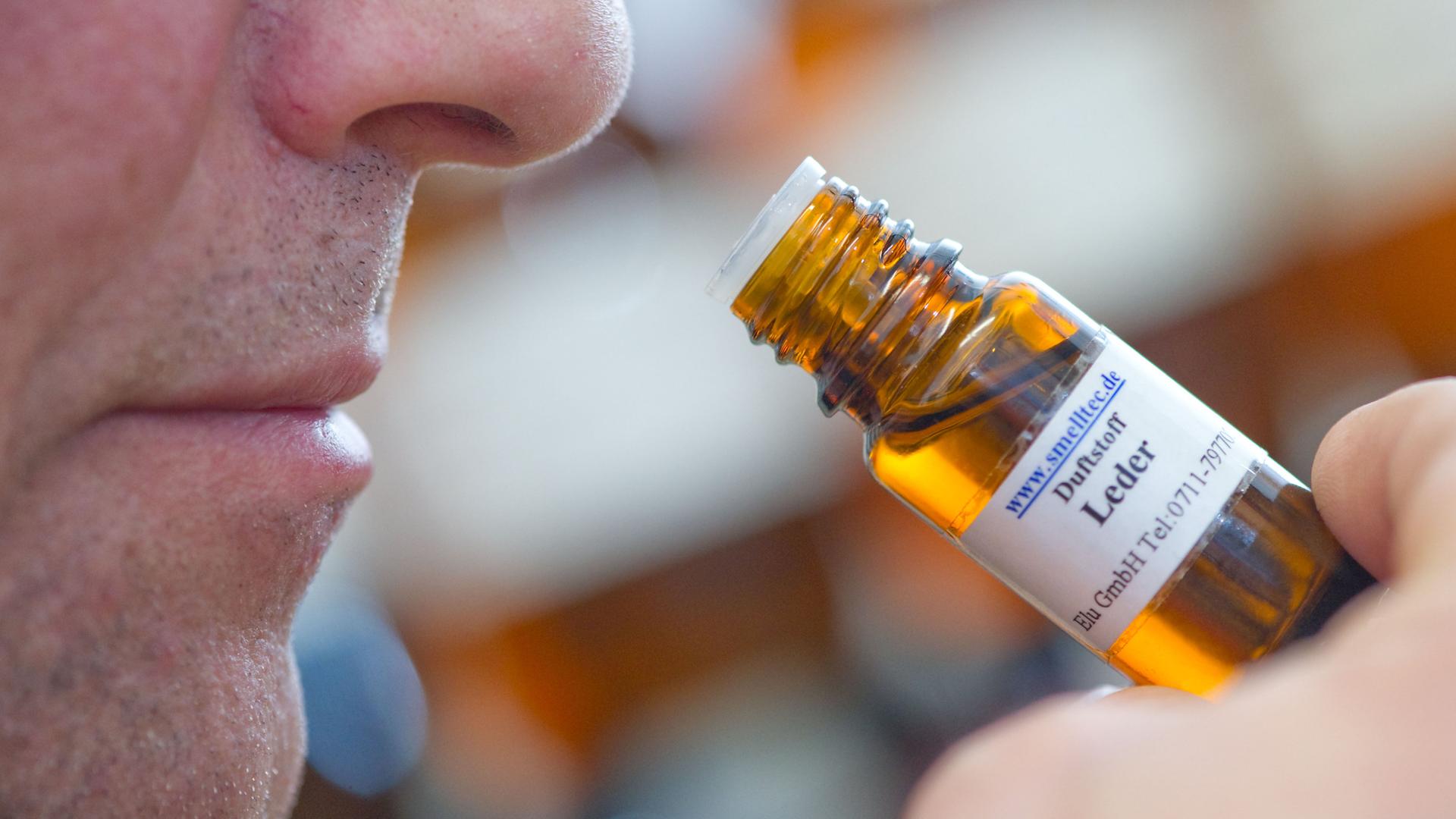 mann riecht an flasche mit duftstoff