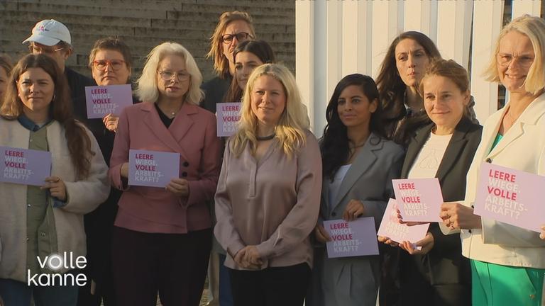 Frauen stehen in einer Reihe und halten Schilder hoch mit der Aufschrift "Leere Wiege, volle Arbeitskraft?"