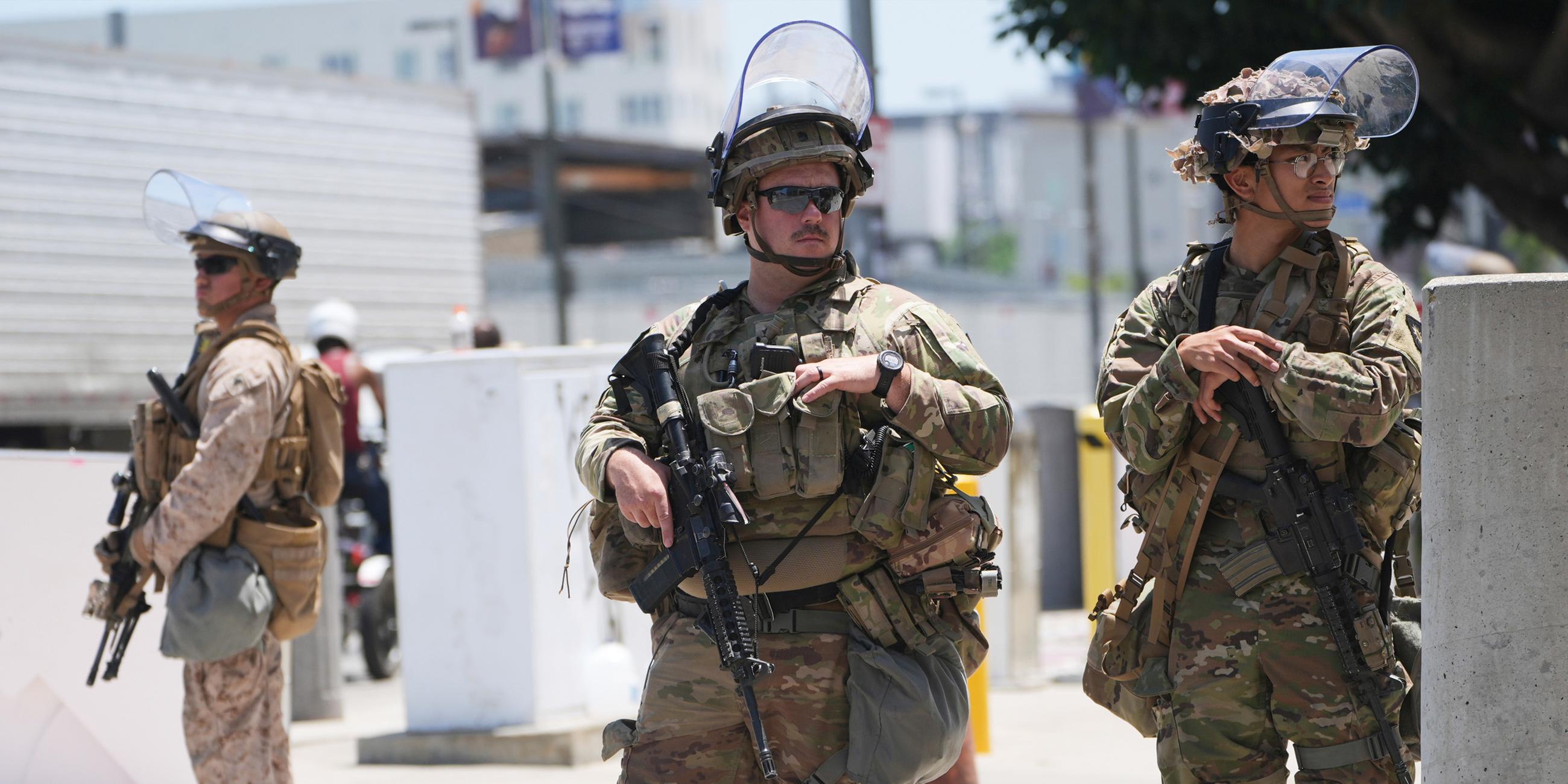 Mitglieder der Californischen National Garde und ein US-Marine bewachen ein Gebäude.