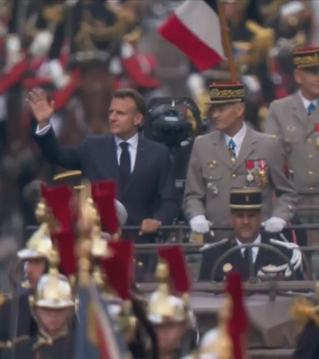 Frankreichs Präsident Emmanuel Macron winkt von einem Fahrzeug bei Militärparade in Paris zum Nationalfeiertag