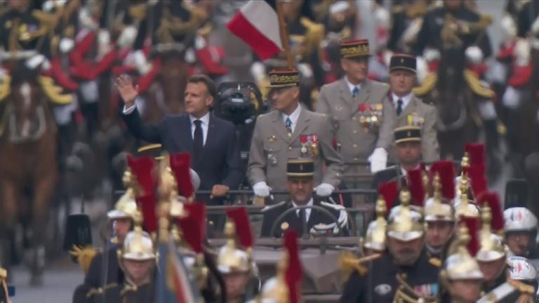 Frankreichs Präsident Emmanuel Macron winkt von einem Fahrzeug bei Militärparade in Paris zum Nationalfeiertag