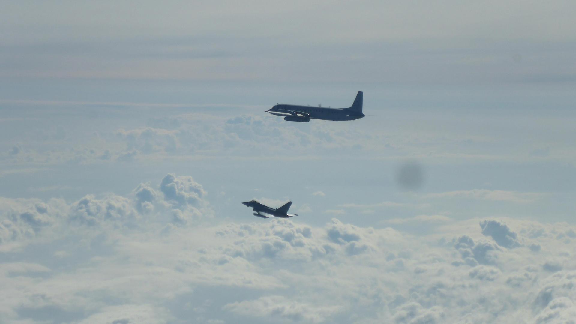 Ein Eurofighter (unten) und ein russisches Flugzeug Il-20M fliegen über der Ostsee. 
