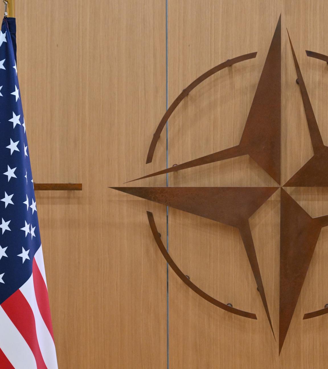 Eine US-Flagge vor einem Hintergrund mit dem Zeichen der Nato.