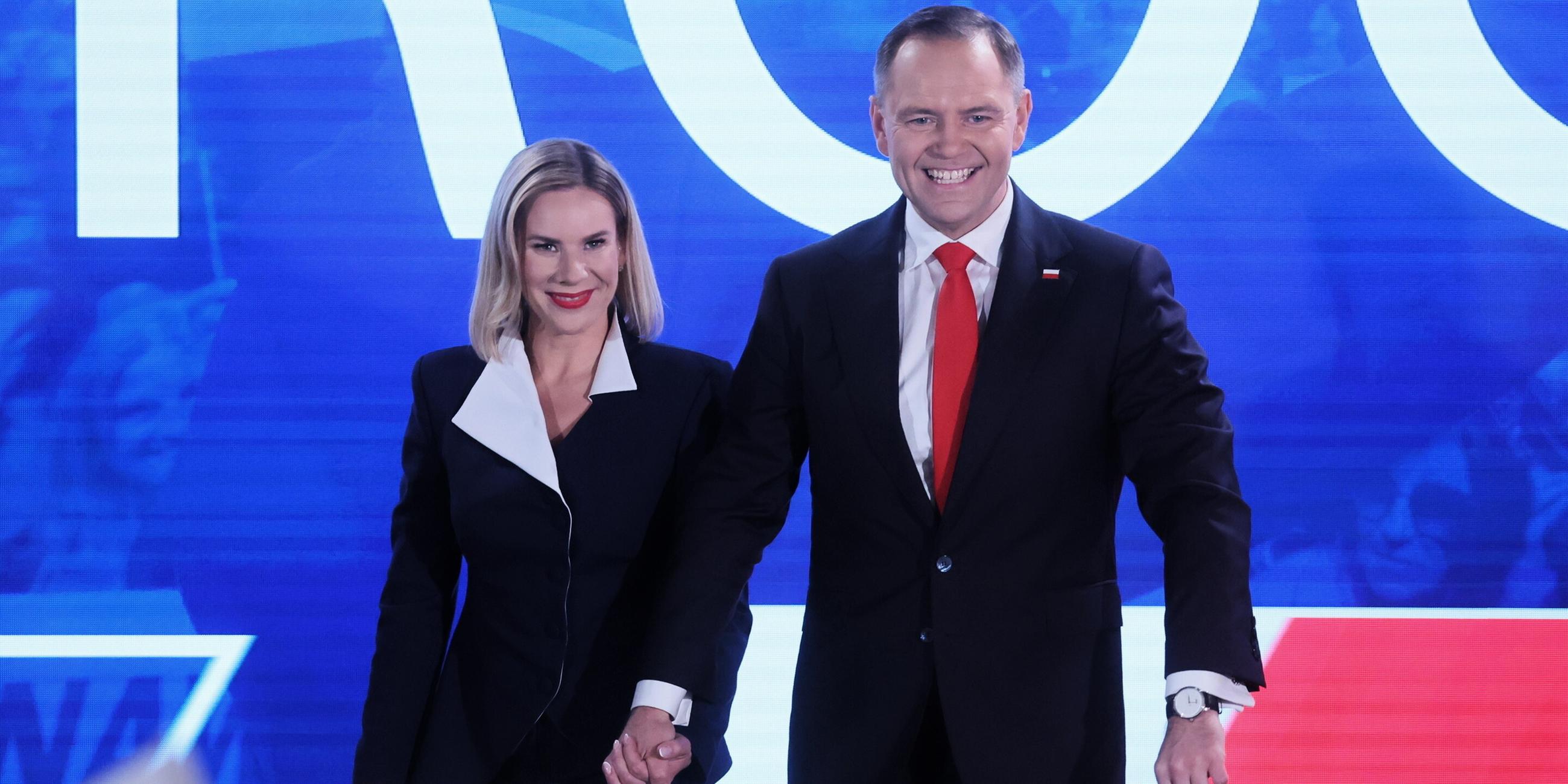 Nawrocki, der die Präsidentschaftswahlgewonnen hat mit seiner Frau. Sie halten sich an der Hand und lachen.