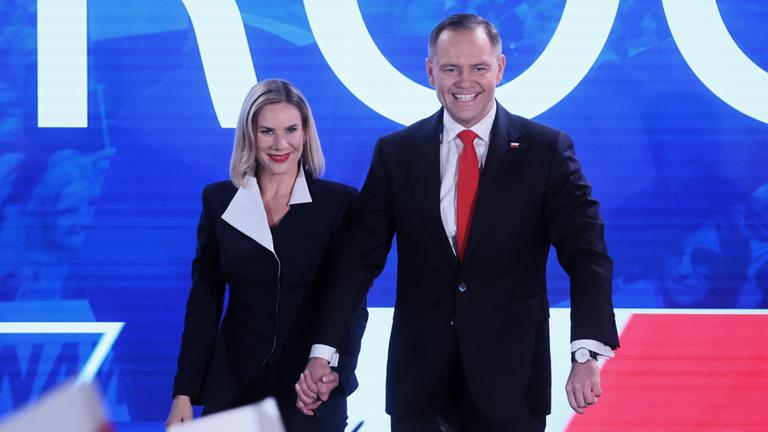 Nawrocki, der die Präsidentschaftswahlgewonnen hat mit seiner Frau. Sie halten sich an der Hand und lachen.