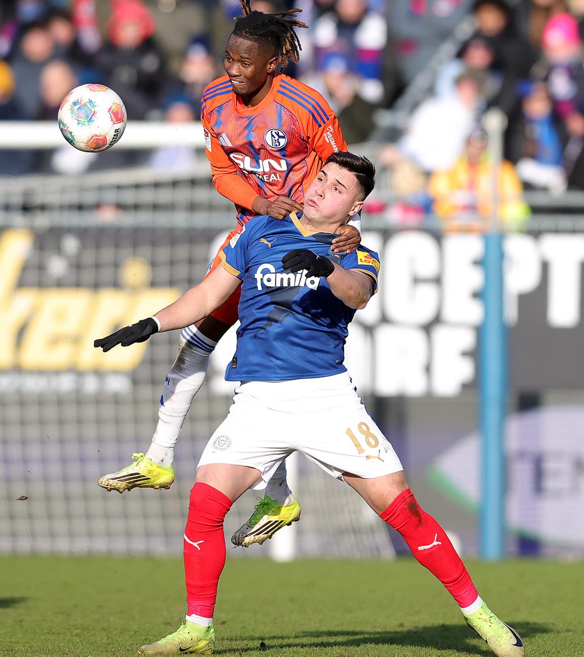 Schalkes linker Verteidiger Moussa Ndiaye springt im Zweikampf mit Kiels Stürmer auf dessen Schulter