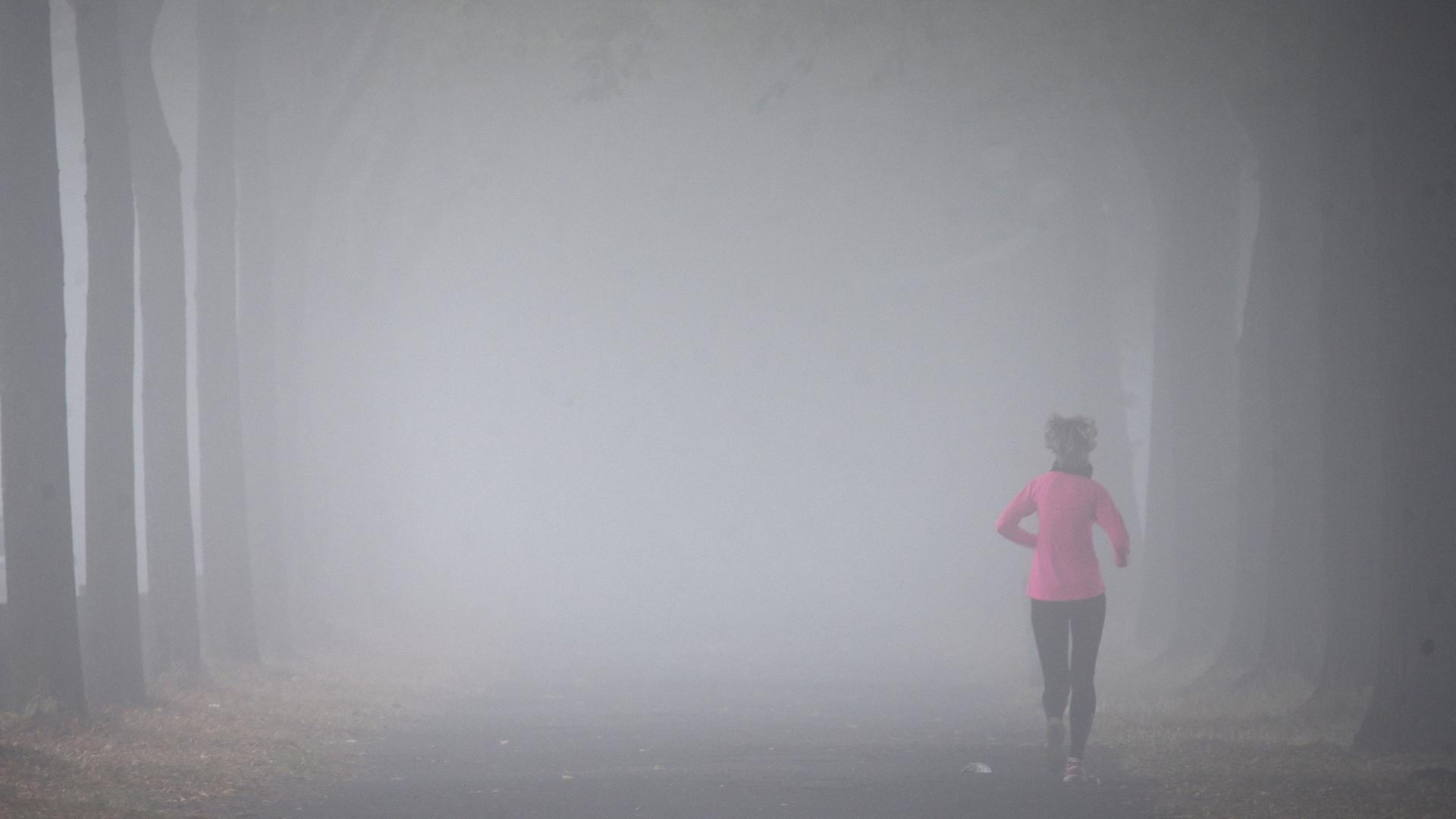 Archiv: Eine Frau joggt im Nebel