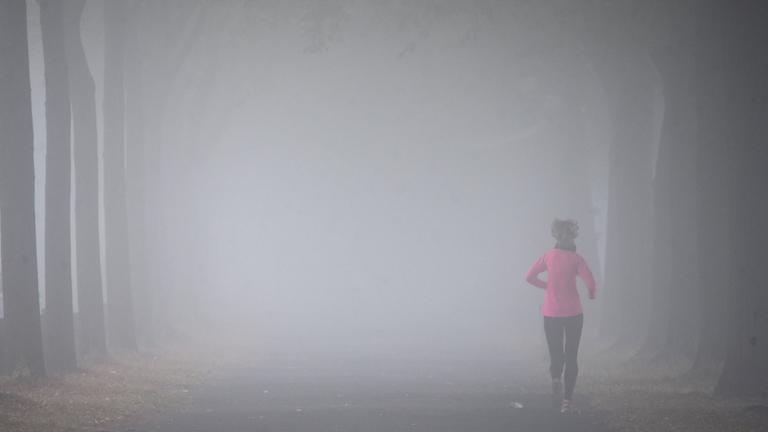 Archiv: Eine Frau joggt im Nebel
