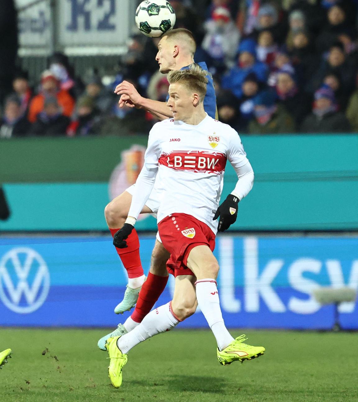 Im DFB-Pokal Viertelfinale kann sich Holstein Kiels Innenverteidiger Ivan Nekic im Zweikampf mit Stuttgarts Flügelspieler Chris Führich per Kopfball durchsetzen