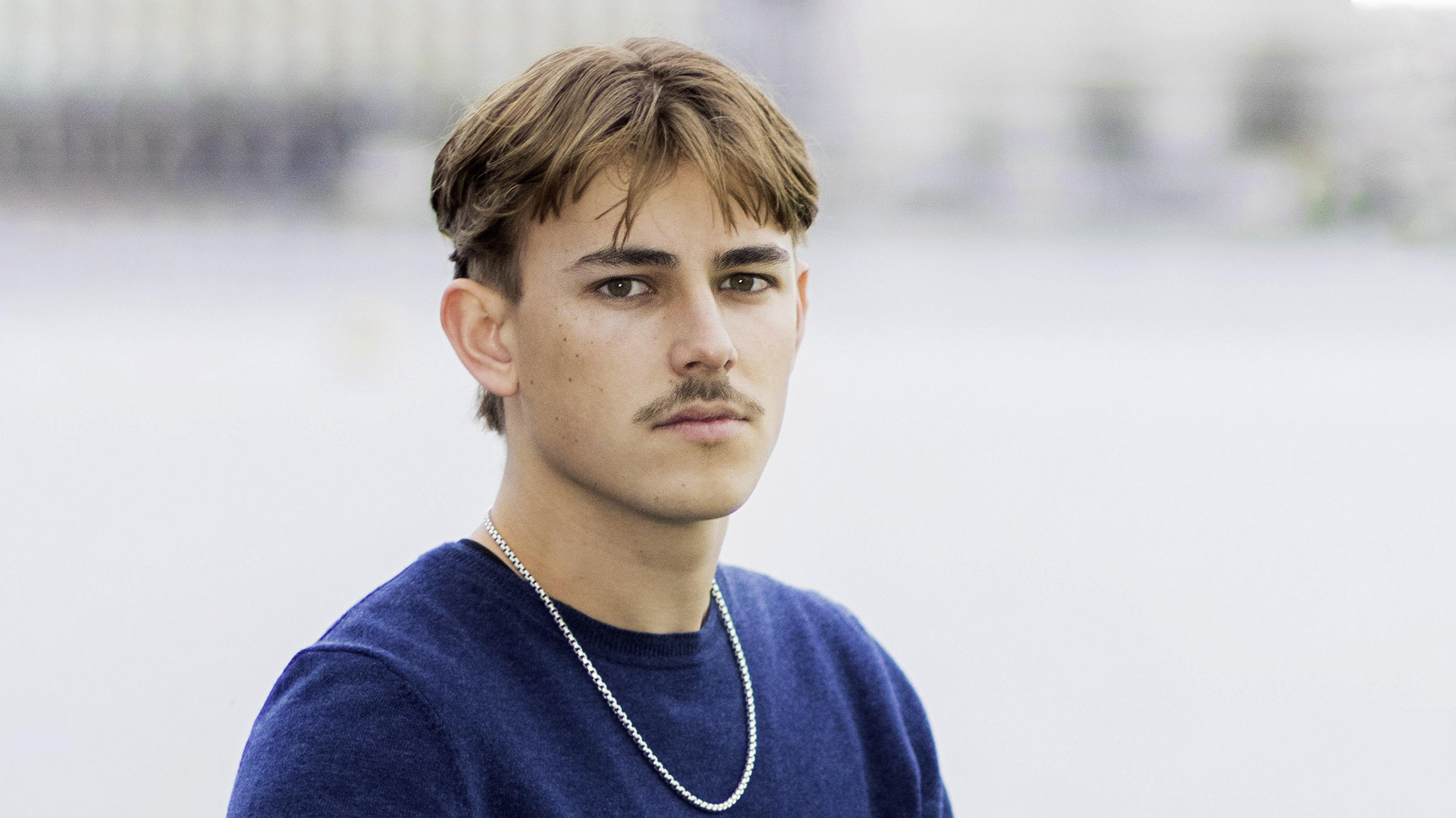 Porträtfoto eines jungen Mannes mit Oberlippenbart.