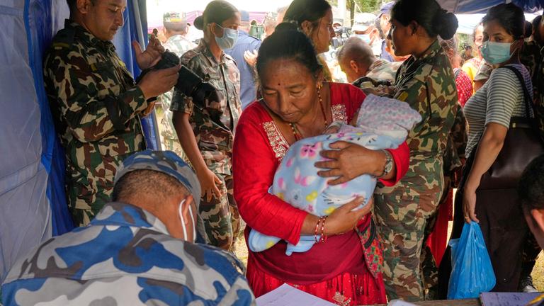 Eine Frau und ihr Kind, die aus einem durch Sturzfluten abgeschnittenen Gebiet gerettet wurden, stehen im Distrikt Nuwakot in Nepal in der Schlange, um sich registrieren zu lassen.