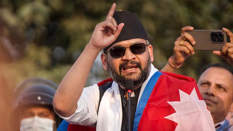 Der zum Regierungschef von Nepal gewählte Balendra Shah spricht an einem Pult und trägt eine nepalesische Flagge um die Schultern.