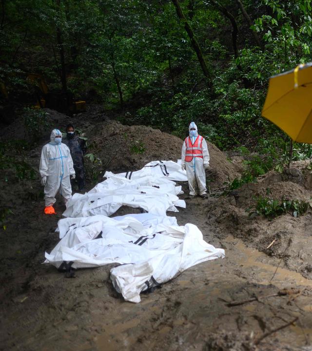Sicherheitskräfte stehen am 1. September 2026 neben nicht identifizierten Leichen von Flutopfern, die im Waldreservat Gokarna in Kathmandu für ein Massenbegräbnis aufgebahrt sind.