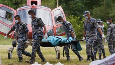 Polizisten tragen Leichensäcke auf einem Hubschrauberlandeplatz im Armeelager in Trishuli im Distrikt Nuwakot, die in einen Hubschrauber verladen werden sollen.
