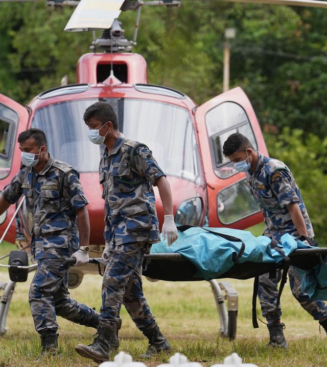 Polizisten tragen Leichensäcke auf einem Hubschrauberlandeplatz im Armeelager in Trishuli im Distrikt Nuwakot, die in einen Hubschrauber verladen werden sollen.