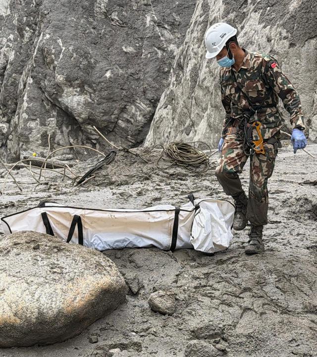 01.09.2026, Nepal, Upper Trishuli: Soldaten der nepalesischen Armee tragen die Leiche eines Arbeiters, die an der Baustelle eines Wasserkraftprojekts in Upper Trishuli, Nepal, geborgen wurde.