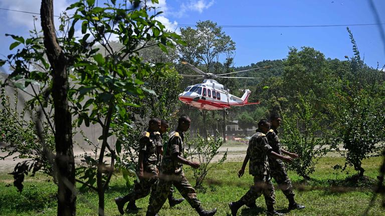 Angehörige der Armee gehen an einem landenden Hubschrauber vorbei, der bei Sturzfluten gerettete Bewohner an Bord hat; Aufnahme aus einem Armeelager in der Ortschaft Battar Bazar im nepalesischen Distrikt Nuwakot vom 27. August 2026. 