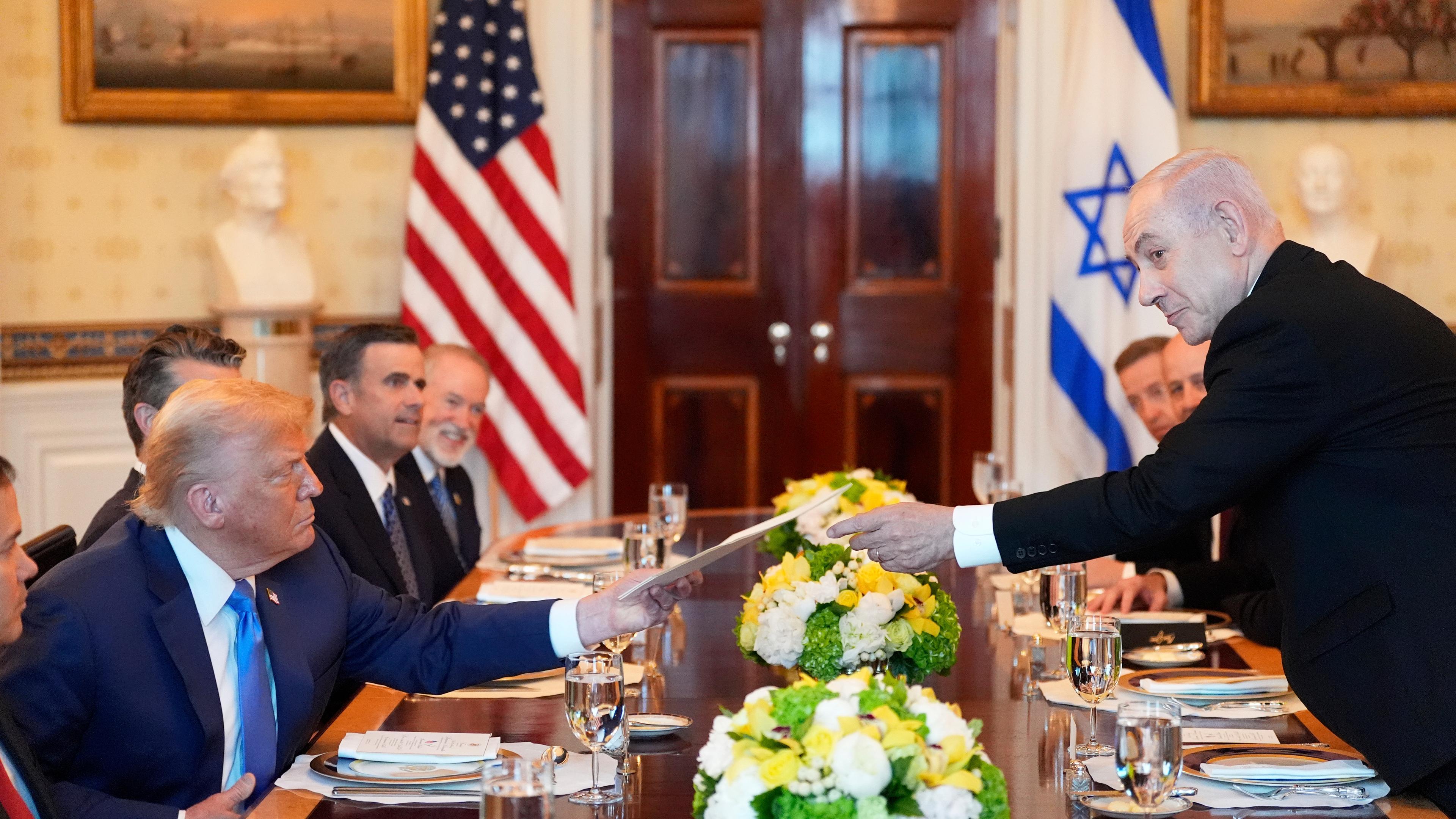 Benjamin Netanjahu (r), Ministerpräsident von Israel, überreicht US-Präsident Donald Trump eine Mappe während eines Treffens im Blue Room des Weißen Hauses in Washington.