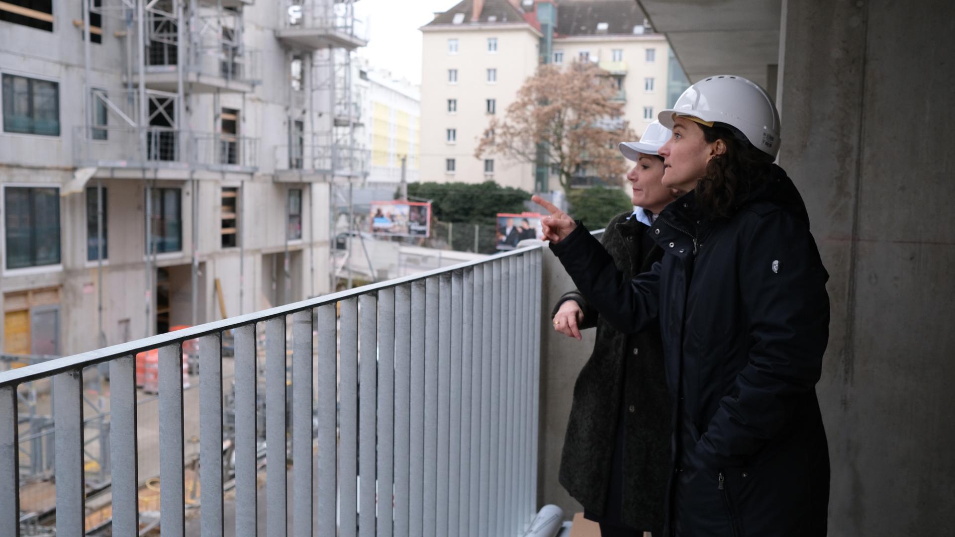 Sarah Zeller steht mit einer weiteren Frau auf einem Balkon und schaut sich den Baufortschritt an.