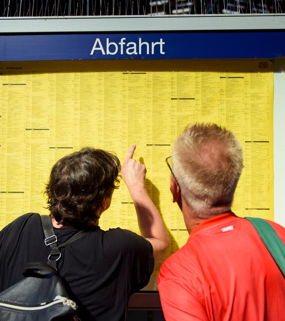 Fahrgäste der Deutschen Bahn stehen vor Fahrplan (Archivfoto)