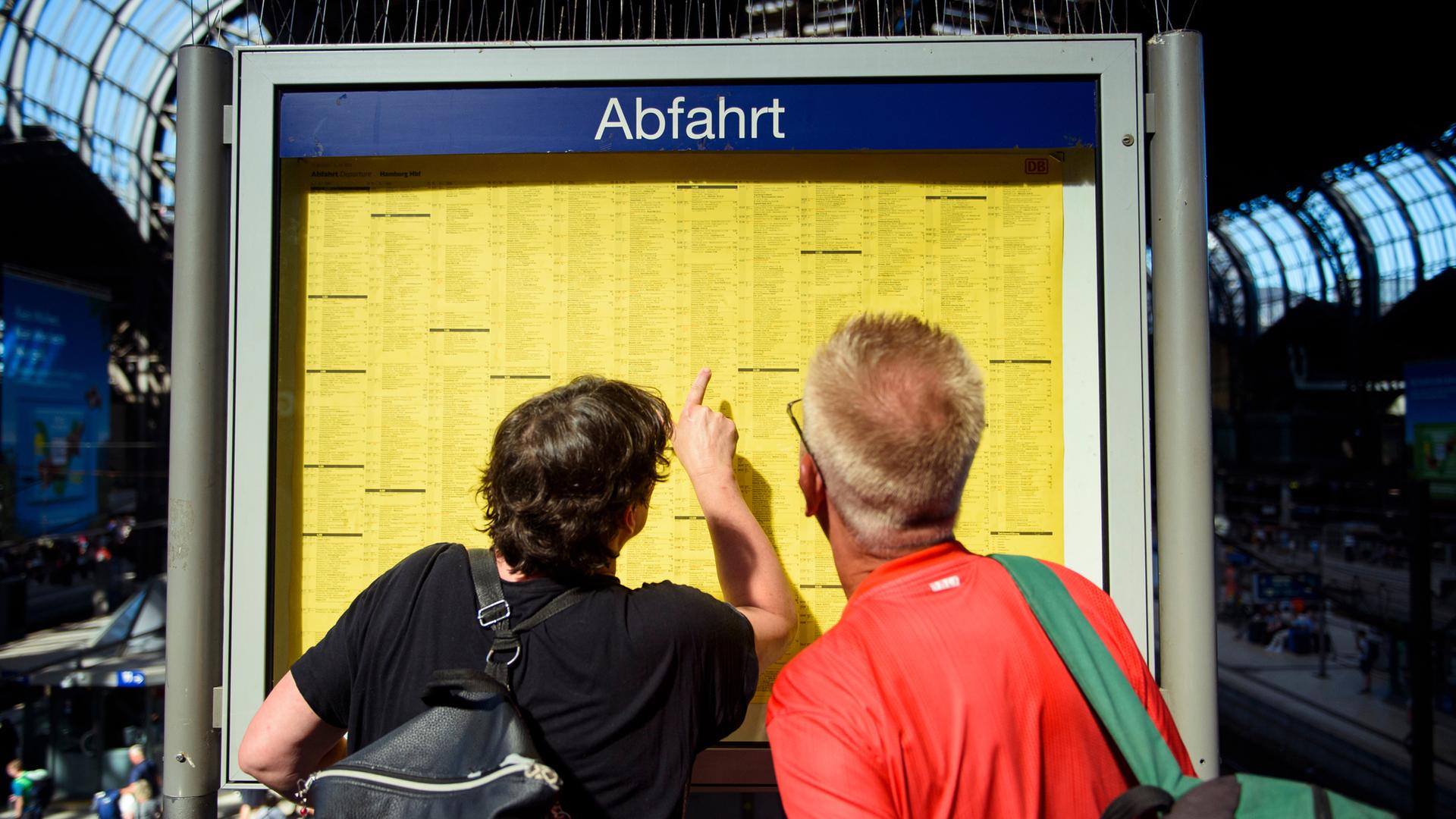 Fahrgäste der Deutschen Bahn stehen vor Fahrplan (Archivfoto)