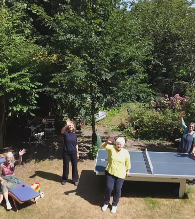 Senioren und Jugendliche im grünen Hof ihrer Wohngemeinschaft