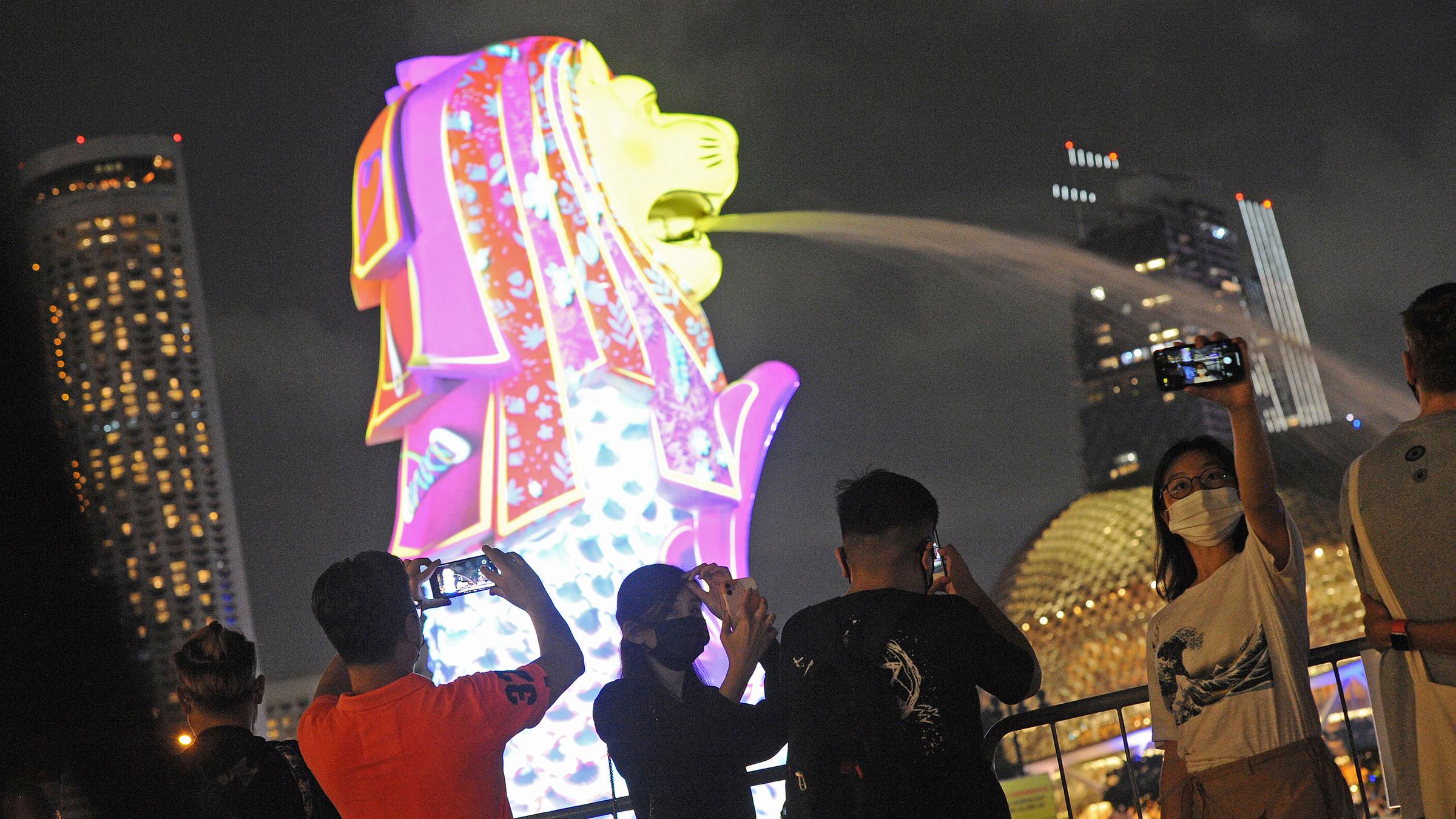In Singapur filmen Zuschauer eine Lichtprojektion, die in der Stadt erleuchten.