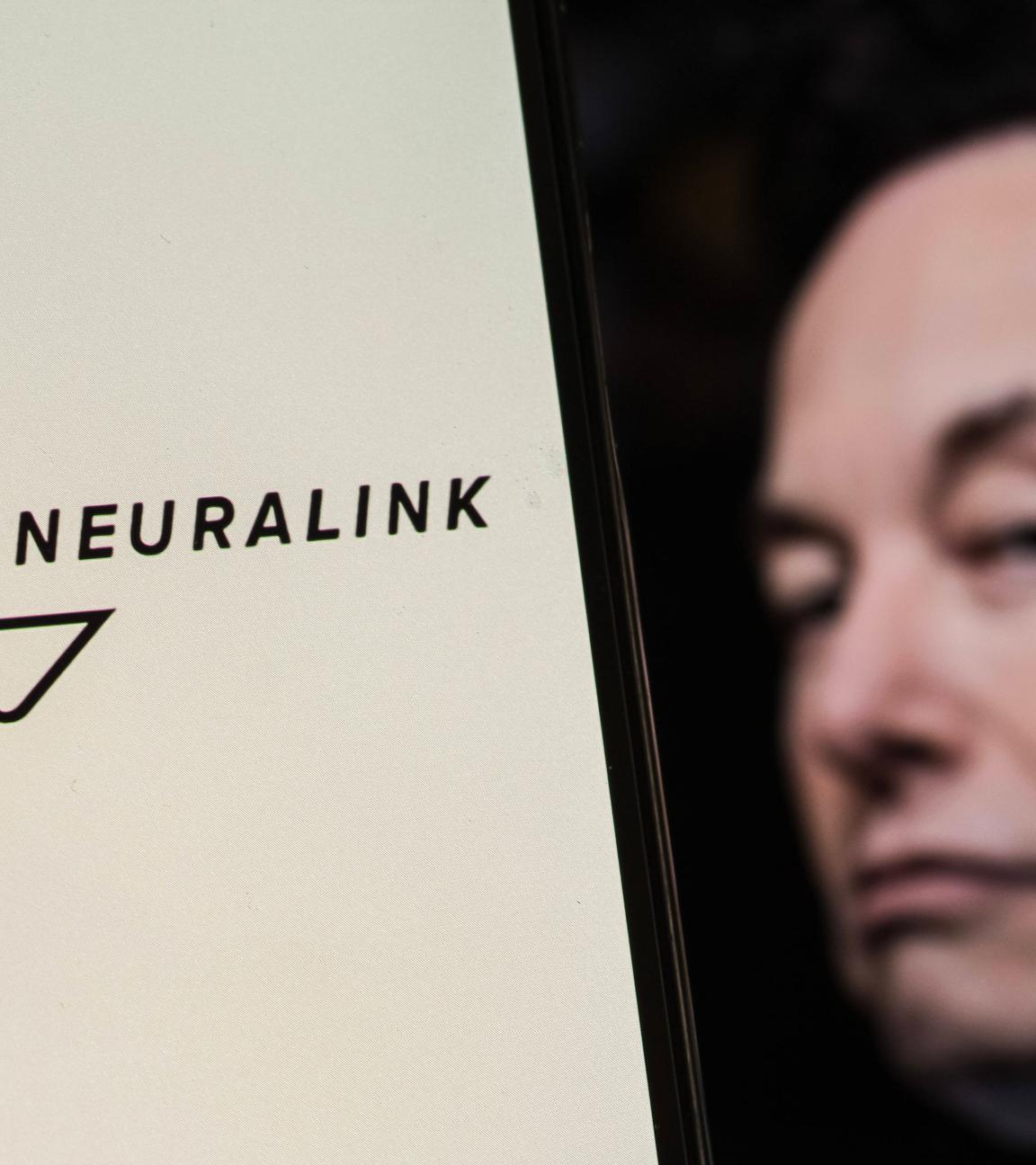 Das Neuralink-Logo ist auf einem Smartphone-Bildschirm mit Elon Musk im Hintergrund zu sehen. 
