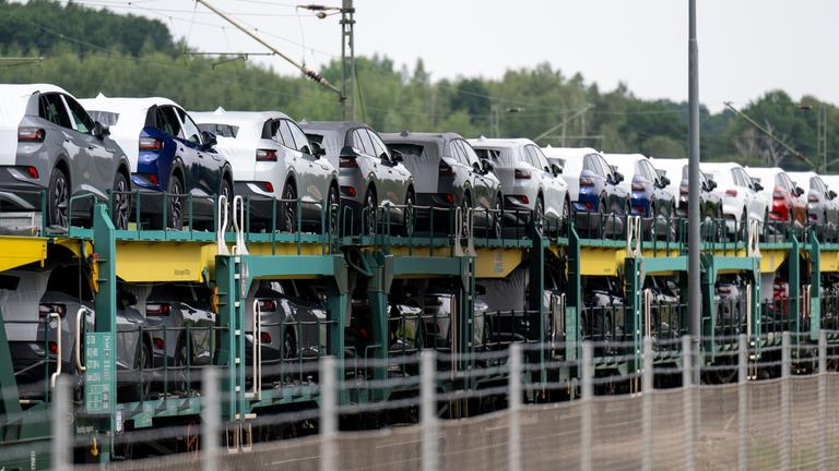 Ein Güterzug mit neuen Elektrofahrzeugen steht neben dem Werksgelände.