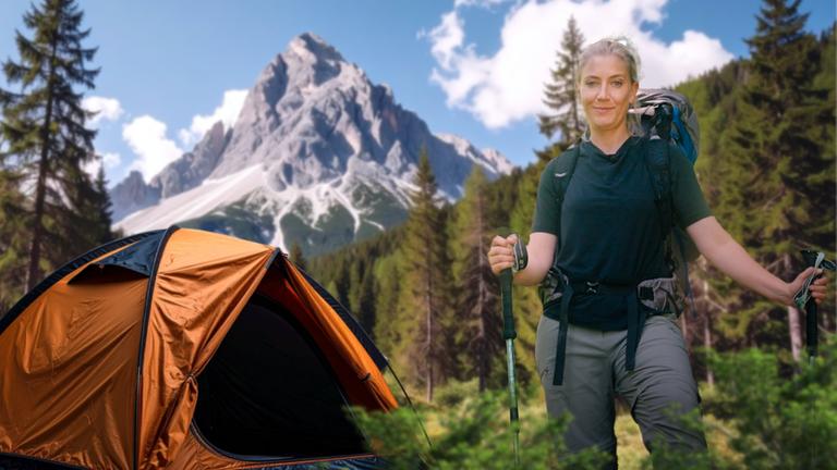 Pia Osterhaus steht in Wanderausrüstung auf einer Lichtung. Im Hintergrund ist ein Wald und ein Bergpanorama zu sehen
