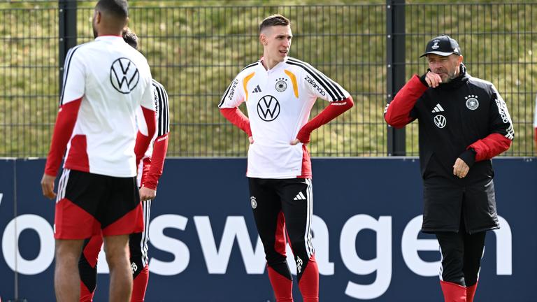 Fußballer Nico Schlotterbeck (mittig) und Co-Trainer Alfred Schreuder (rechts) stehen auf dem Platz während des Abschlusstrainings der deutschen Nationalmannschaft am 26.03.2026 in Herzogenaurach, Bayern.