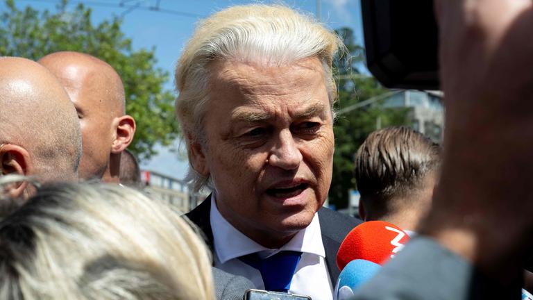 Mann mit Warnweste, Auto und im Vordergrund zwei Europaflaggen