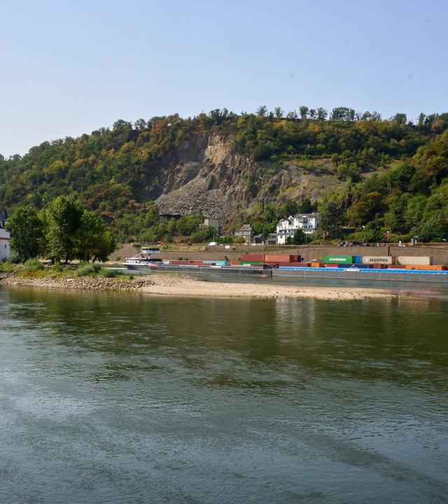 Ein Containerschiff mit reduzierter Ladung passiert die auf einer Felseninsel im Rhein errichtete Zollburg Pfalzgrafenstein. 