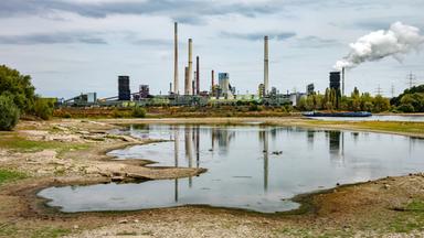 Niedrigwasser am Rhein vor einer Industrieanlage in Duisburg im Ruhrgebiet.