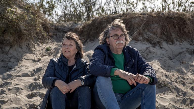 Ulla und Didi Högel sitzen nebeneinander auf eine Sanddüne.