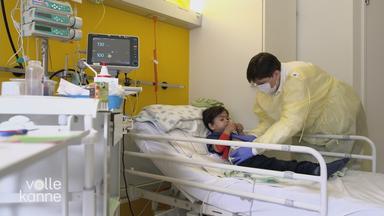 Pflegekraft brtastet Bauch eines Kindes auf Krankenbett