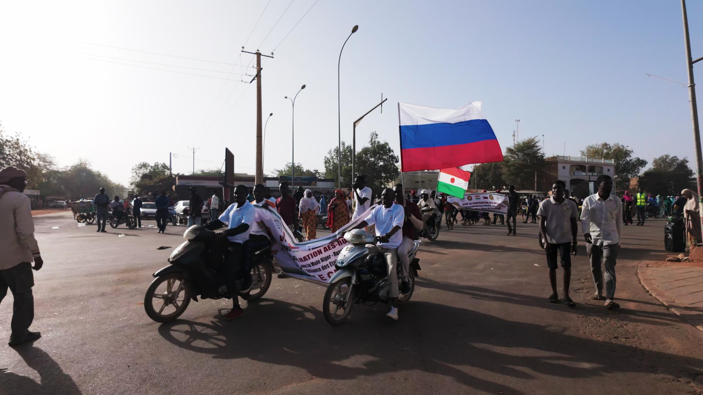 Ein Mann auf einem Motorrad hält eine Russlandflagge in der Hand.