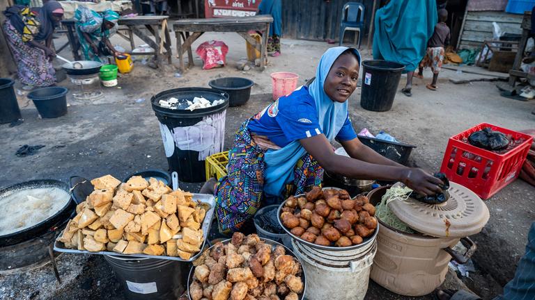 Eine Frau baut in Minna, Nigeria ihren Verkaufsstand mit Lebensmittel auf.