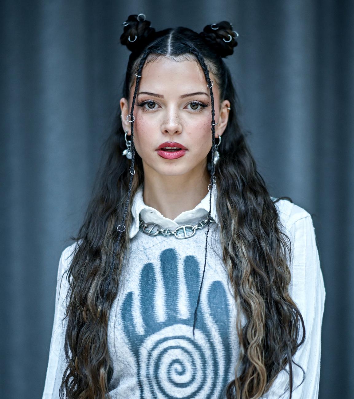 Nina Chuba steht vor einem schwarzen Vorhang. Das Bild ist im Porträtformat aufgenommen.